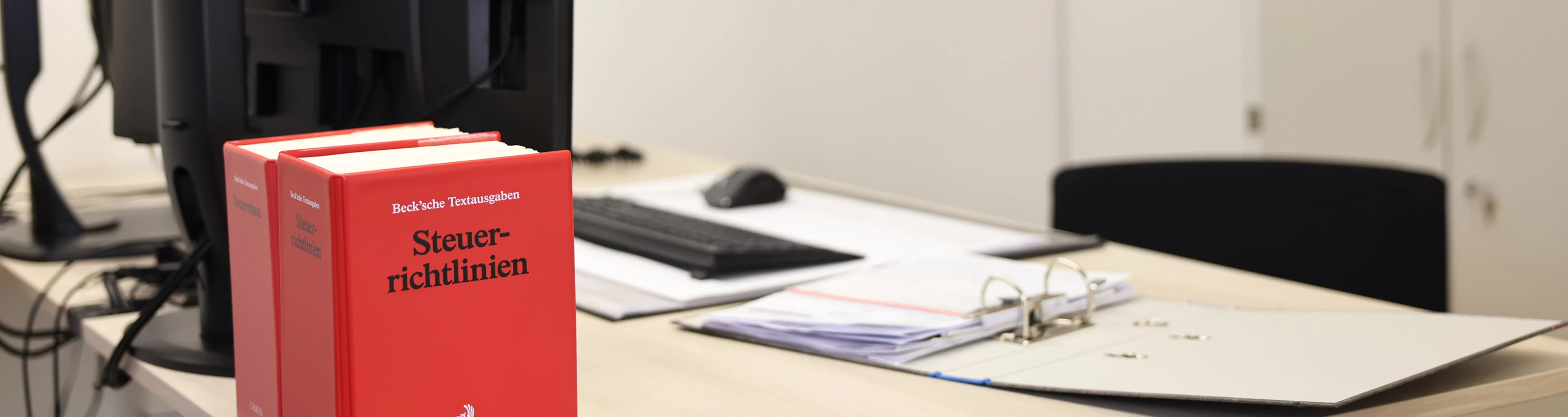 Ein Büro der Kanzlei Kann + Partner und auf dem Tisch stehen Bücher und ein Ordner.