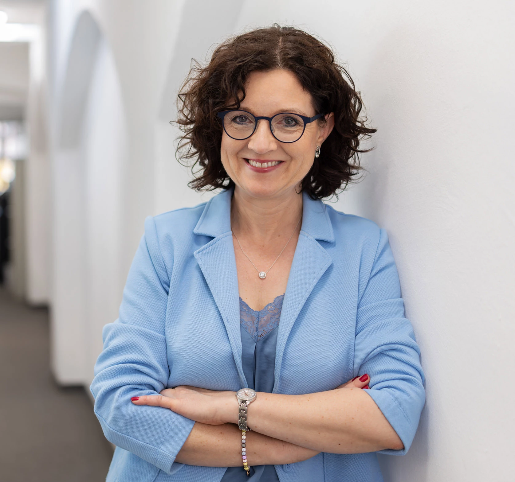 Tanja Deinhart steht lächelnd an einer Wand